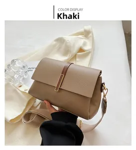 Detail of khaki pebbled leather crossbody bag with wide strap and gold hardware accents