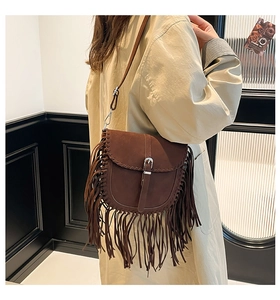 Détail d'un sac besace en daim marron avec de longues franges porté par un mannequin
