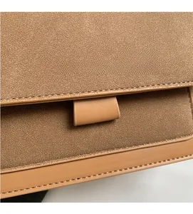 Close-up of brown suede crossbody bag with premium leather trim and FASHION & BAGS logo