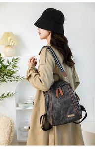 Detail of dark grey canvas backpack with brown leather trim and geometric pattern strap