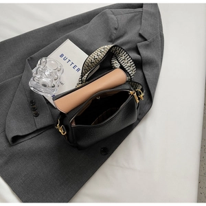 Detail view of black pebbled leather crossbody bag with wide strap and gold hardware