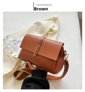 Close-up of brown litchi pattern leather texture and gold metal buckle on crossbody bag