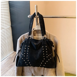 Détail d'un sac cabas en daim noir avec clous argentés et large bandoulière à anneau