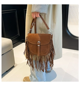 Détail du sac besace vintage en daim marron avec franges et bords tressés sur le rabat