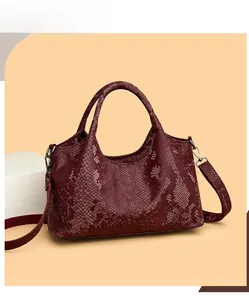 Macro view of burgundy snakeskin texture on a high-capacity tote bag with silver hardware