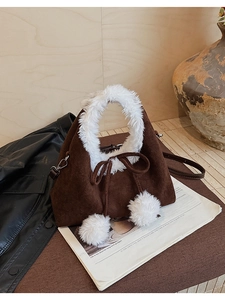 Detail of coffee suede bucket bag with white faux fur trim and fluffy decorative pom-poms