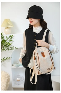 Detail of beige backpack featuring brown leather accents and silver metal zippers