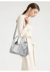 Detail of silver snake-pattern tote bag with metallic texture on a model shoulder