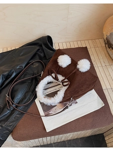 Detail of corduroy bucket bag with faux fur trim and decorative white pom-pom drawstrings