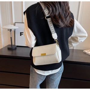 White pebbled leather crossbody bag with patterned wide strap shown on a model