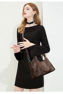 Detail view of dark brown snake-embossed handbag with silver hardware and shoulder strap