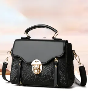 Detail of black crossbody bag featuring snakeskin texture and metallic clasp closure
