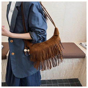 Detail of bohemian caramel suede shoulder bag with long fringes and wooden beads