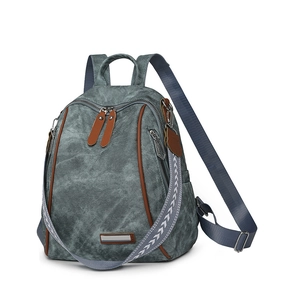 Close-up of gray canvas backpack with brown leather trim and silver metal logo tag