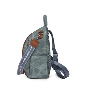 Detail of gray-blue canvas backpack featuring brown leather trim and tribal woven strap