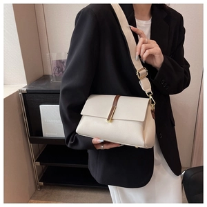 Detail of minimalist beige textured crossbody bag with brown leather strap and gold buckle