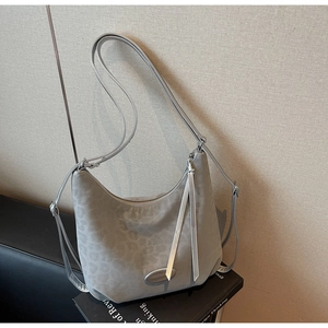 Macro detail of grey leopard print hobo bag with silver strap and elegant fringe decor