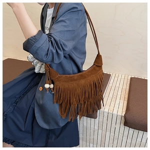 Detail of brown suede hobo bag featuring long tassels and decorative bead pendant