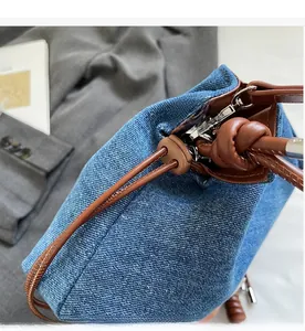 Detail of blue denim bucket bag featuring brown leather drawstring and silver metal hardware
