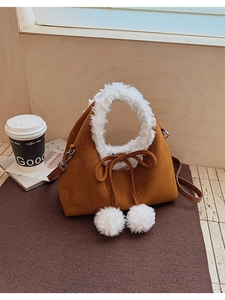 Close-up of brown suede bucket bag with white plush trim and fuzzy pom-pom drawstrings