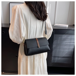 Rear view of model wearing a black litchi pattern small square bag with wide strap