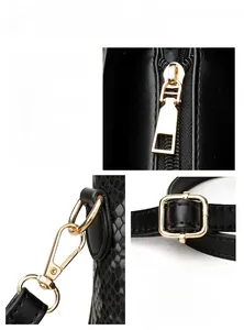 Detail of black faux snake skin texture and gold metal hardware on women's crossbody bag