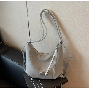 Detail of grey leopard print suede hobo bag with white tassels and silver metal hardware