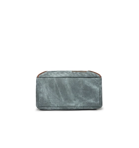 Detail of grey-blue canvas toiletry bag with brown leather trim in a rectangular shape