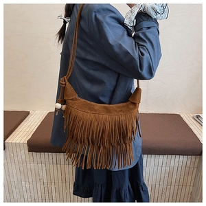 Close-up of brown suede hobo bag with long tassels and decorative shoulder strap beads