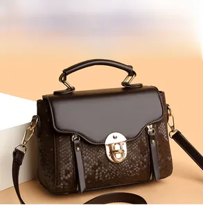 Detail of dark brown retro crossbody bag with snakeskin texture and gold metal lock