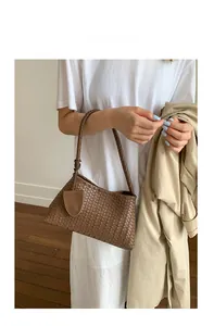 Close-up of brown leather woven handbag with classic Intrecciato craft and round handle