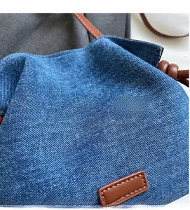 Detail of blue denim fabric texture and brown leather strap with precise stitching