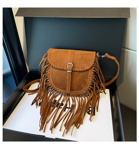 Détail d'un sac besace en daim marron avec de longues franges et des coutures tressées