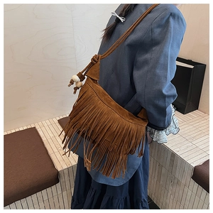 Detail of vintage brown suede hobo bag featuring long tassels and wooden bead strap knots