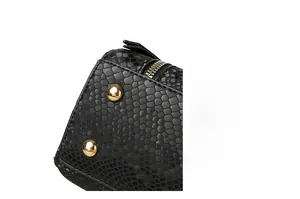 Detail view of the black snake skin texture bag base with golden protective metal studs