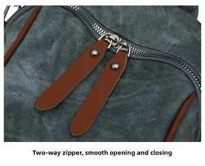Detail of teal canvas backpack showing smooth two-way metal zipper with brown leather pulls