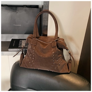 Détail d'un cabas en daim marron foncé avec clous argentés et finitions bohèmes rétro chic