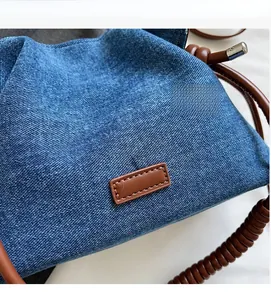 Detail of denim fabric and brown leather handle on a vintage pleated cloud bucket bag