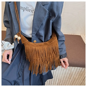Detail of brown suede tassel shoulder bag with wooden beads in a bohemian style