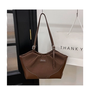 Λεπτομέρεια καφέ δερμάτινης τσάντας shopper με υφασμάτινη υφή και μεταλλικό σήμα