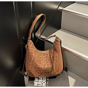 Macro detail of brown leopard print hobo bag showing zipper tassel and metal logo