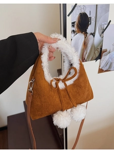 Close-up of caramel bucket bag with white plush trim and decorative pom-pom tassels
