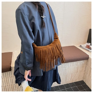 Detail of a vintage dark brown suede crescent bag featuring long decorative tassels
