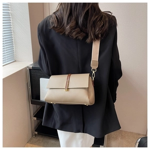 Detail of khaki leather crossbody bag with wide strap and gold hardware on model