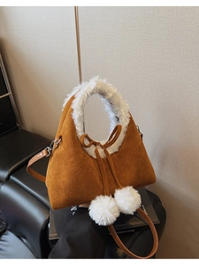 Detail of winter bucket bag featuring brown suede fabric and white faux fur trim with pom poms