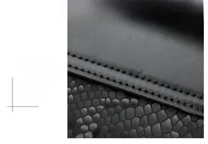 Close-up of black crossbody bag featuring smooth leather and snakeskin textured embossing