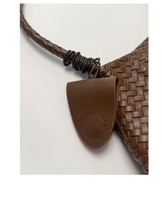 Dettaglio macro della trama in pelle intrecciata marrone scuro e patta della borsa