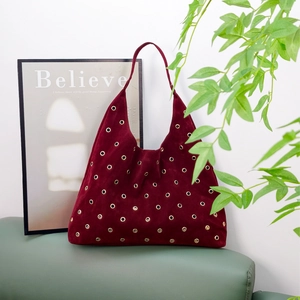 Vintage burgundy suede tote bag with golden studs on a stylish leather sofa