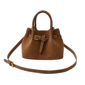 Brown suede bucket handbag with gold buckle and adjustable strap on white background