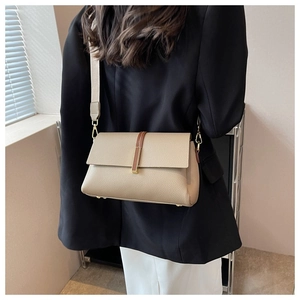 Detail of lychee textured leather crossbody bag with golden buckle and wide strap